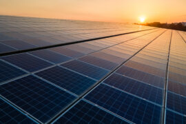 Blue photovoltaic solar panels mounted on building roof for producing clean ecological electricity at sunset. Production of renewable energy concept.