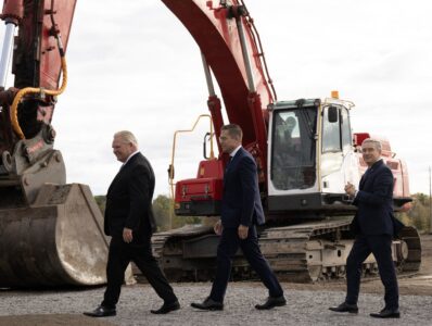 Ontario Premier Doug Ford, Umicore CEO Mathias Miedreich and Innovation and Science and Industry Minister Francois-Philippe Champagne make their way past heavy equipment to a ceremonial ground breaking ceremony, in Millhaven, Ont., Monday, Oct. 16, 2023.